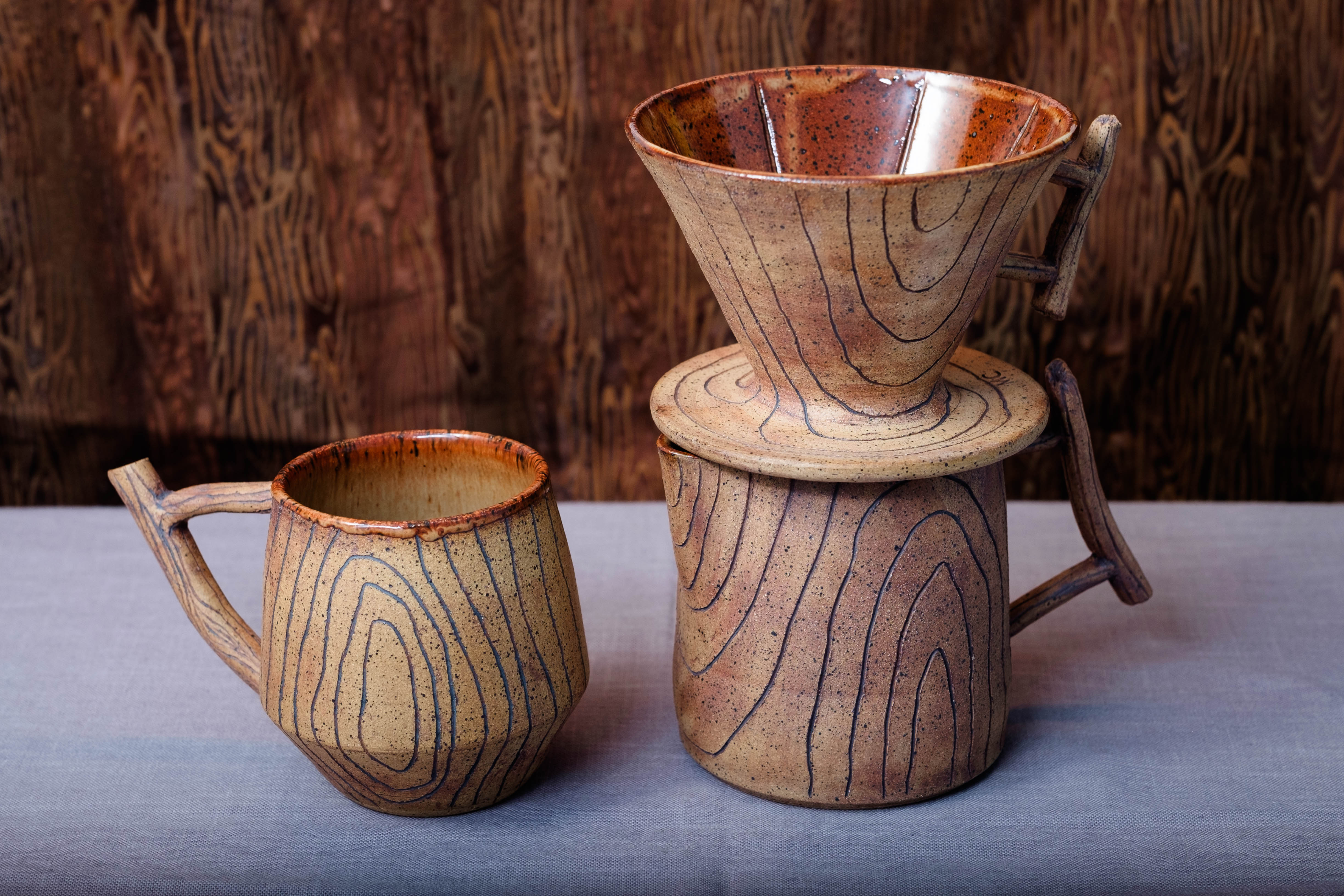 A woodgrain coffee cup, pitcher, and coffee dripper